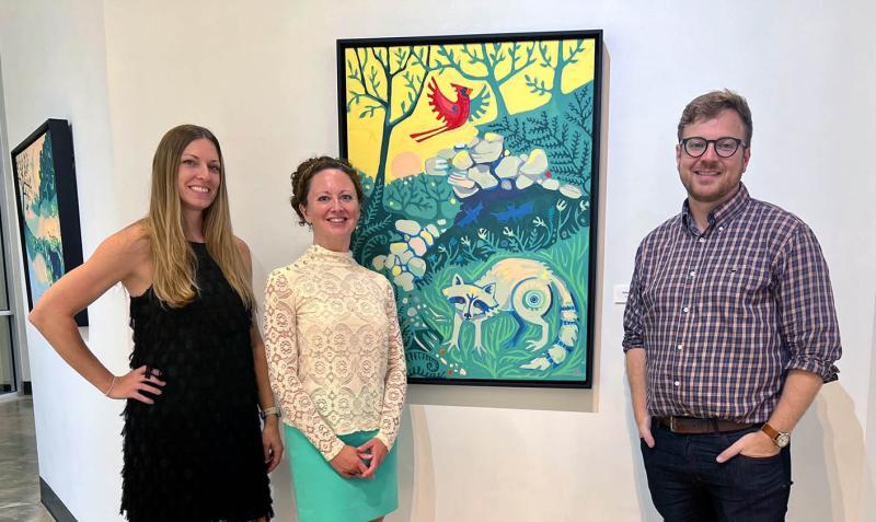 Two gallery staff pose with artist Adam Trest next to a painting.